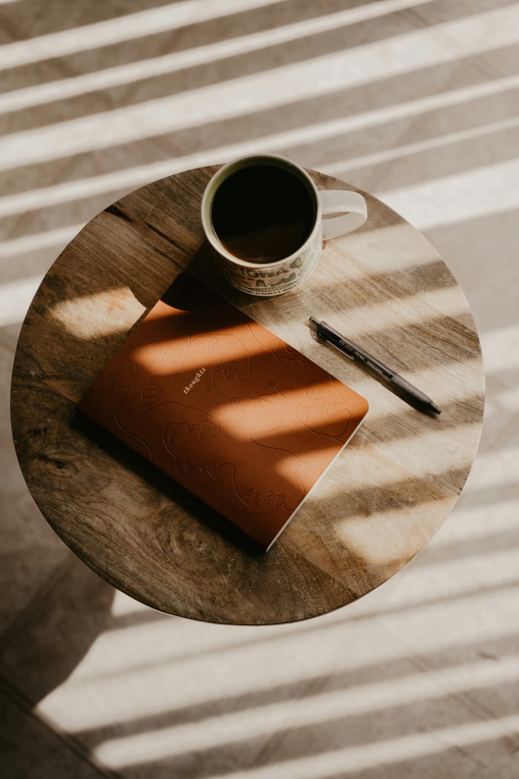 A cup of coffee, a journal, and a pen on a small wooden table in morning light, a calm space for EMDR therapy reflection