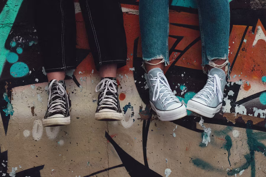 Two teenagers' sneakers dangling over a graffiti-painted ledge, at ease side by side